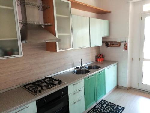 a kitchen with green cabinets and a sink and a stove at Casa Vacanze Brezza Marina with beautiful garden in Quartu SantʼElena