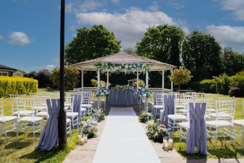 a wedding ceremony with white chairs and a gazebo at Park Hall Hotel and Spa Wolverhampton in Wolverhampton