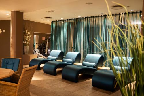 a waiting room with blue chairs and a table at Home Hotel Havnekontoret in Bergen