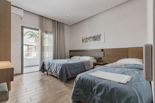 a hotel room with two beds and a window at Hotel Golden Sun in Néa Meságkala