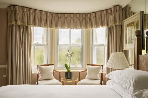 a bedroom with a bed and two chairs and a window at Milestone Hotel Kensington in London