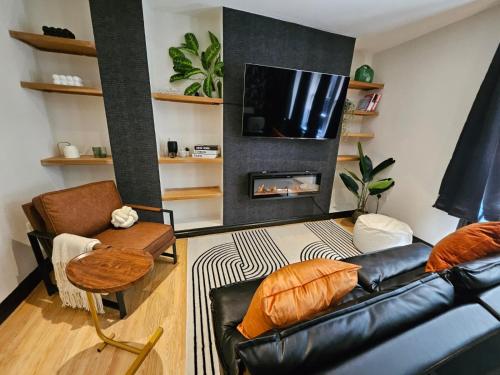 a living room with a black leather couch and a fireplace at INNit Blue Sky in Brighton & Hove