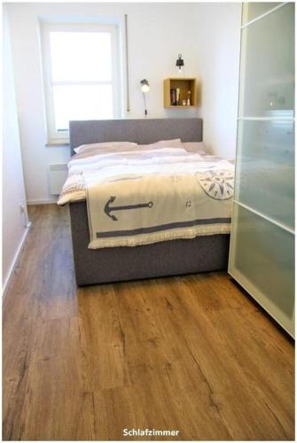 Un dormitorio con una cama y suelo de madera. en Hafenblick Orth, en Orth