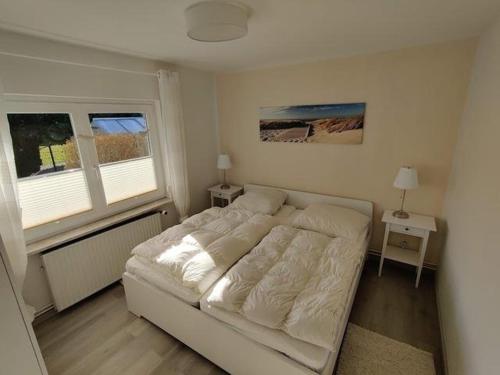 a white bed in a room with two windows at Hus Kalli in Landkirchen