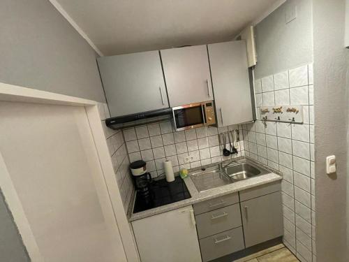 a small kitchen with a sink and a microwave at Kaleu in Burgtiefe auf Fehmarn 