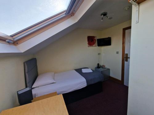 a small bedroom with a bed and a window at Hotel 65 in London