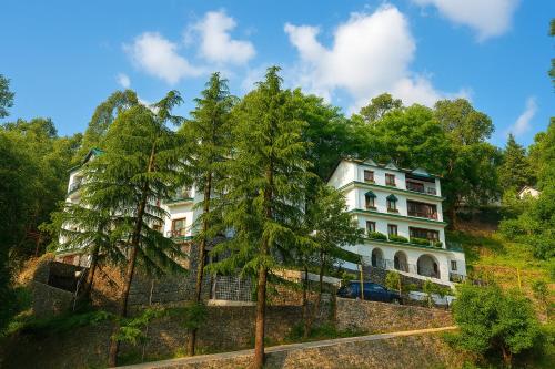 a building on a hill with trees in front of it at Vilãsa Lall Ji Resort in Dalhousie
