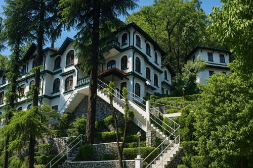 a large white house with stairs leading up to it at Vilãsa Lall Ji Resort in Dalhousie