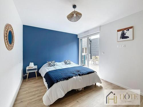 a bedroom with a blue accent wall and a bed at L'Instant Elégant - Plage à 100m in Bray-Dunes