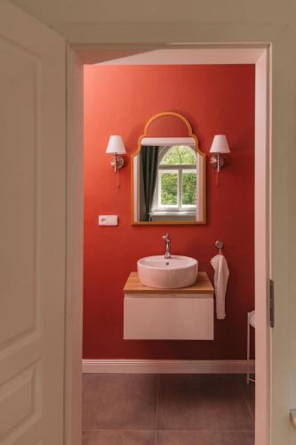 a red bathroom with a sink and a mirror at Zámecká Stodola - Červený Hrádek u Sedlčan in Sedlčany