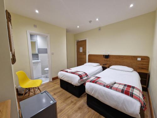 a hotel room with two beds and a yellow chair at Hotel 65 in London