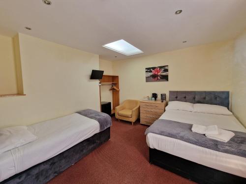 a hotel room with two beds and a chair at Hotel 65 in London