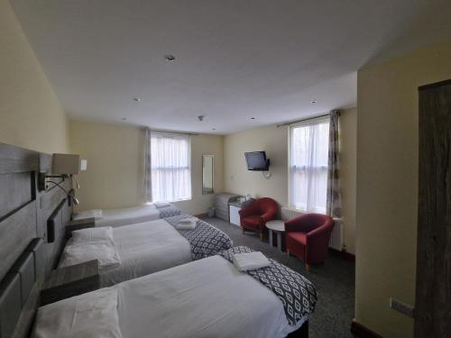 a hotel room with two beds and a couch at Hotel 65 in London