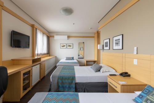 a hotel room with two beds and a tv at Monreale Plus Guarulhos International Airport in Guarulhos