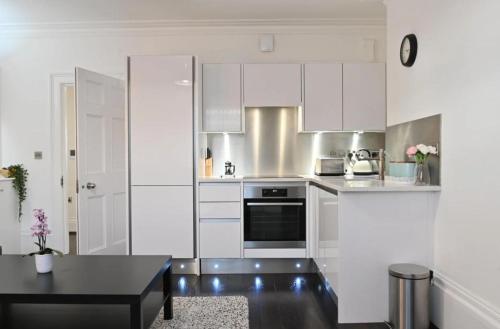 cocina con armarios blancos y mesa negra en River & Hospital Base, Kings Road Retreat, en Reading