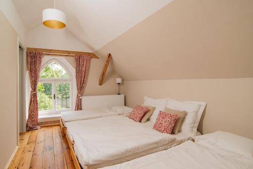 two beds in a room with a window at Zámecká Stodola - Červený Hrádek u Sedlčan in Sedlčany