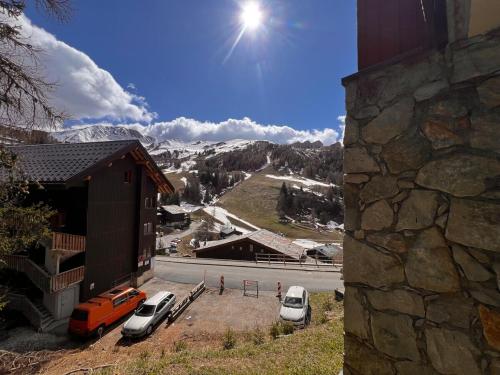 2 voitures garées dans un parking à côté d'un bâtiment dans l'établissement Appartement piscine, sauna, skis, à La Plagne Tarentaise