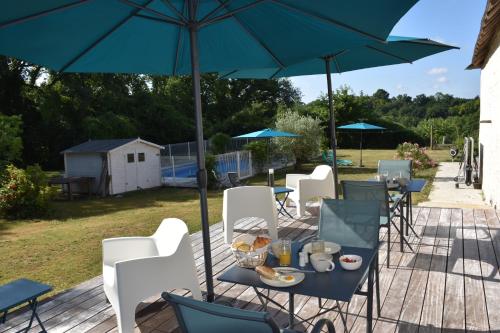 a table and chairs under an umbrella on a deck at Chambres d'hôtes PANCHIEN in Nouzilly
