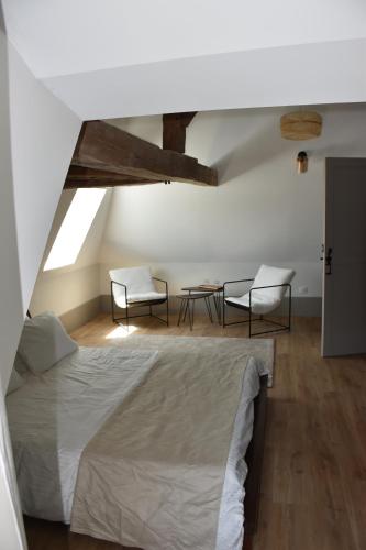 a bedroom with a bed and two chairs and a table at Chambres d'hôtes PANCHIEN in Nouzilly