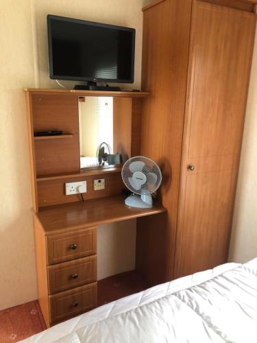 a bedroom with a dresser with a tv and a fan at Lincolnshire Sunrise Views in Mablethorpe