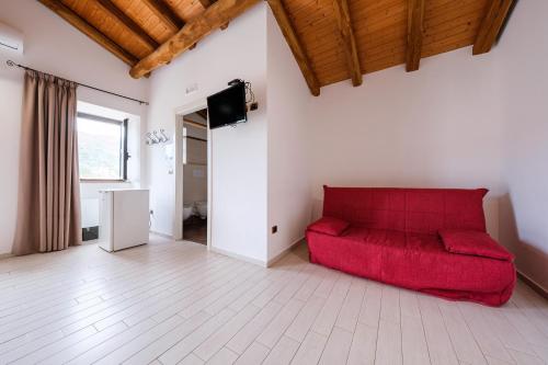 a living room with a red couch and a television at Antico Casale Gioiosa Marea in Gioiosa Marea