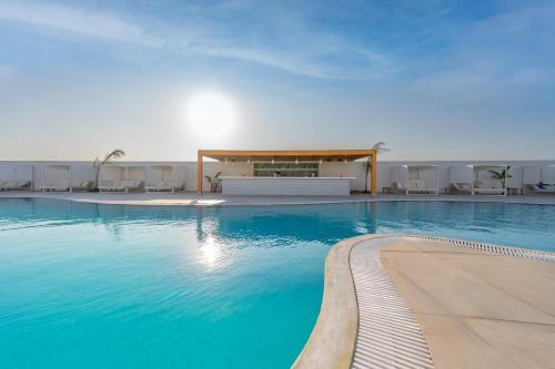 a swimming pool with blue water in front of a building at Smy Kos Beach & Splash in Mastichari