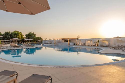 a large swimming pool with chairs and umbrellas at Smy Kos Beach & Splash in Mastichari