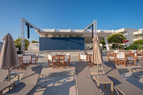 a patio with tables and chairs and umbrellas at Smy Kos Beach & Splash in Mastichari