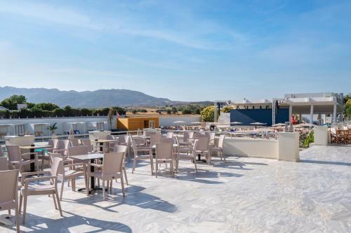 a patio with tables and chairs on a roof at Smy Kos Beach & Splash in Mastichari
