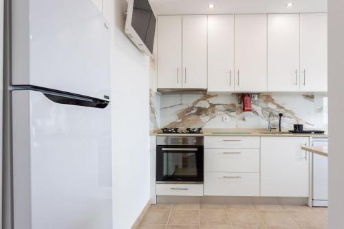 a white kitchen with white cabinets and appliances at Almada Lisbon em frente dos transportes públicos in Almada