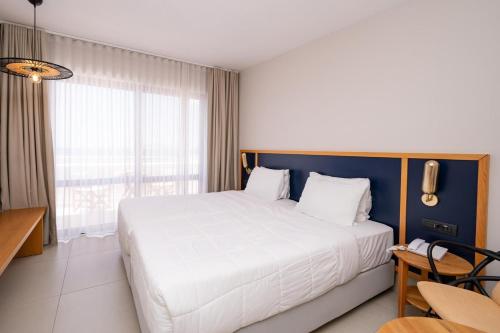 a bedroom with a large white bed and a window at Smy Kos Beach & Splash in Mastichari