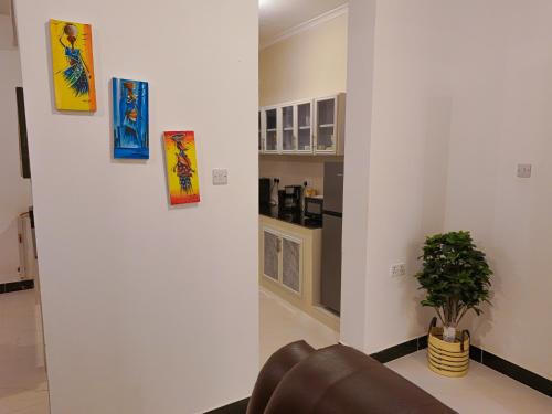 a living room with a couch and paintings on the wall at 2BR Beachfront Apartment with Balcony & Sea Views - Uroa, Zanzibar in Uroa
