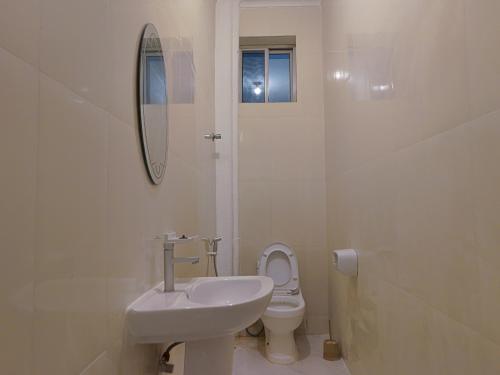 a white bathroom with a sink and a toilet at 2BR Beachfront Apartment with Balcony & Sea Views - Uroa, Zanzibar in Uroa