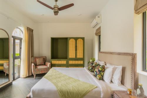 a bedroom with a bed and a chair at BellaVie 3-BHK Villa With Private Pool & TV Lounge Area in A Gated Complex in Siolim