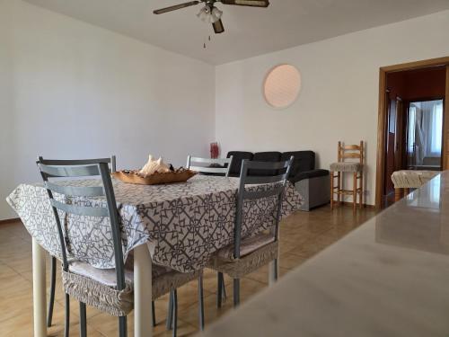 a dining room table with four chairs and a ceiling fan at SunTan - Waves and Peaks Retreat in Mascali