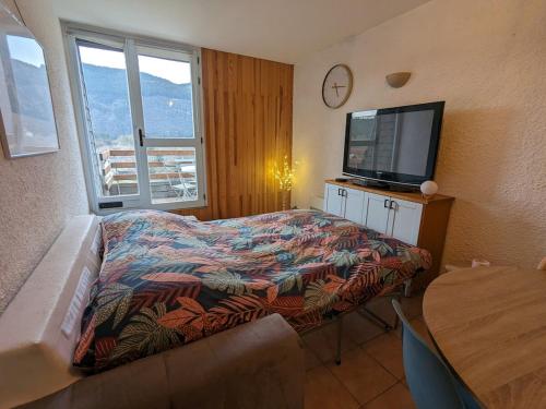 a bedroom with a bed and a flat screen tv at La Terrasse du Tarn in Ispagnac