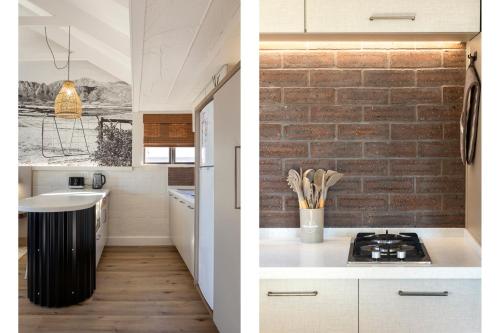 a kitchen with white counters and a brick wall at Hornbill House Self Catering Accommodation in Hermanus