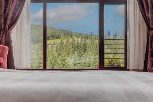 a bedroom with a large window with a view of a mountain at Bukovel Apart in Bukovel
