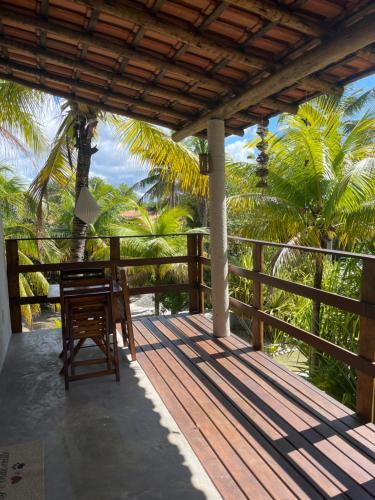 een houten veranda met een tafel en stoelen erop bij Jardim do Wape in Santa Cruz Cabrália