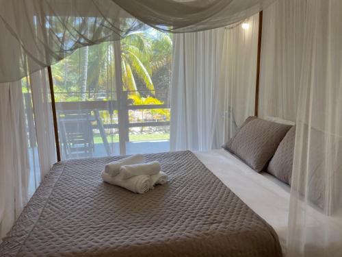 een bed met een handdoek en een raam bij Jardim do Wape in Santa Cruz Cabrália