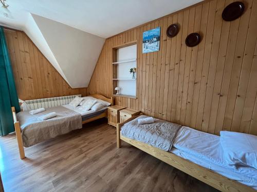 Dos camas en una habitación con paredes de madera. en Na Wzgórzu, en Czarna Góra
