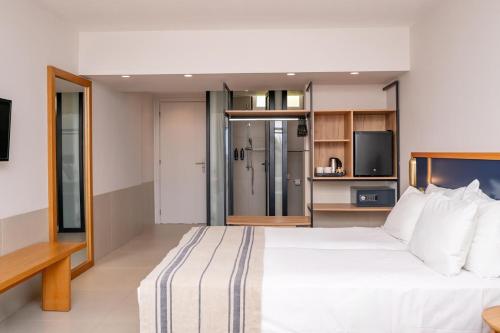 a bedroom with a large white bed and a kitchen at Smy Kos Beach & Splash in Mastichari