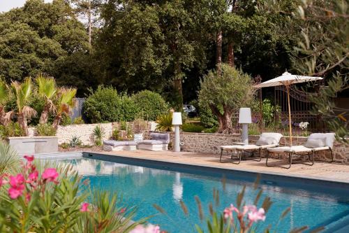 a swimming pool with chairs and an umbrella at Villa Po'Strophe - Bâtiment classé avec piscine in Clisson