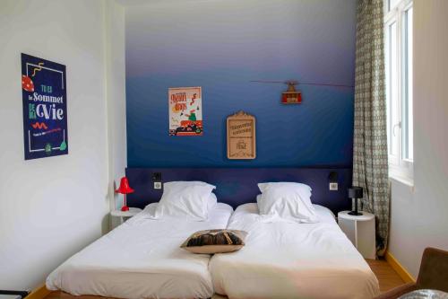 a bedroom with two beds with a blue wall at B&B HOME Brides-les-Bains Les 3 Vallées in Brides-les-Bains