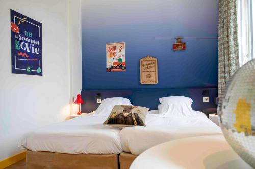 two beds in a room with a blue wall at B&B HOME Brides-les-Bains Les 3 Vallées in Brides-les-Bains