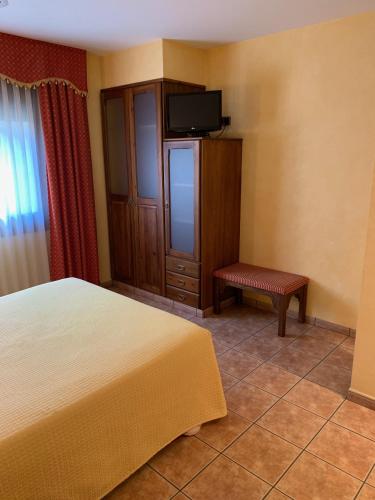 a bedroom with a bed and a tv and a bench at Hotel Restaurant Cal Petit in Oliana