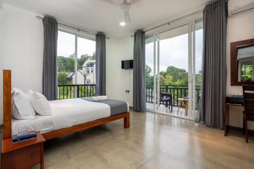 - une chambre avec un lit et un balcon avec des fenêtres dans l'établissement Mo Green, à Kandy