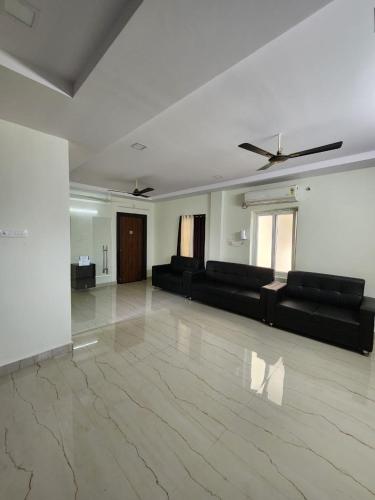 a living room with black furniture and a marble floor at Happy stays in Vijayawāda