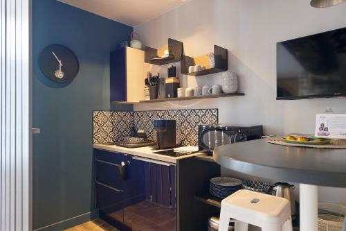 a small kitchen with blue cabinets and a counter at Villa Po'Strophe - Bâtiment classé avec piscine in Clisson