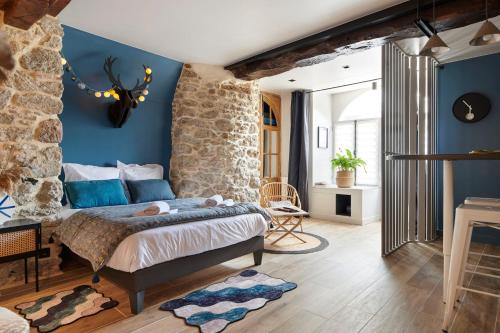 a bedroom with blue walls and a stone wall at Villa Po'Strophe - Bâtiment classé avec piscine in Clisson